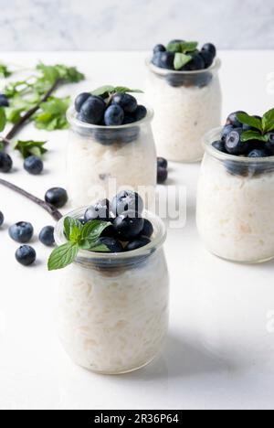 Budino di riso con mirtilli in diversi vasetti di vetro Foto Stock