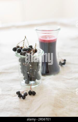 Fresche bacche di Aronia e fatti in casa a base di bacche di Aronia succo in bicchieri Foto Stock