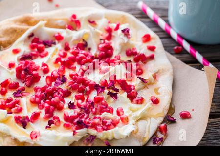 Un piatto con formaggio cremoso di capra, semi di melograno e petali di rosa Foto Stock