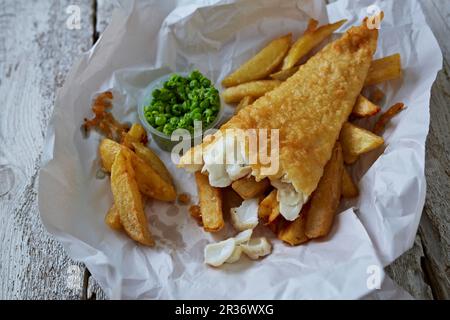 Pesce e patatine fritte con piselli di funghi sulla carta Foto Stock