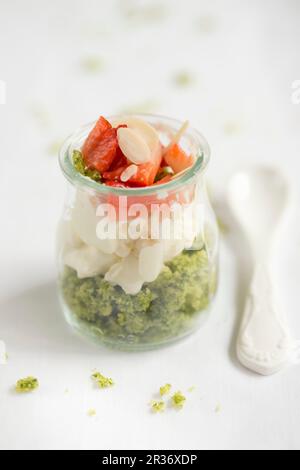 Un dolce a strati in un vaso di vetro con torta di spinaci, panna e fragole Foto Stock