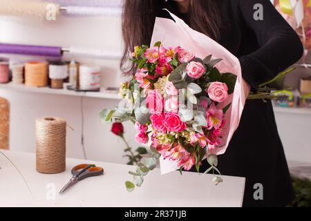 Fioraio rendendo il bouquet con rose Foto Stock