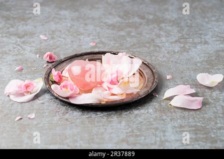 Quarzo rosa con petali di rosa su un piatto d'argento Foto Stock