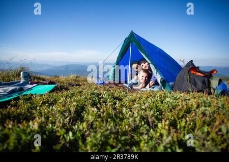 La famiglia guarda fuori dalla tenda Foto Stock