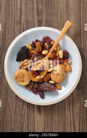 Frutta secca e noci in una ciotola con un cucchiaio di legno Foto Stock