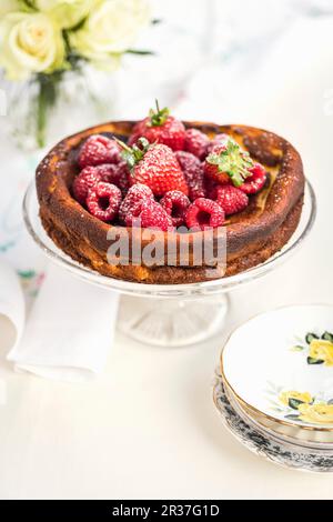 Cheesecake di Quark a basso contenuto di grassi con bacche fresche su un supporto per torte Foto Stock