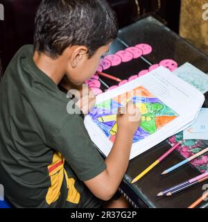 Smart Indian Little boy disegno con matite colorate kit di vari colori durante le vacanze estive, cute Indian Kid Sketching disegno colorato Foto Stock