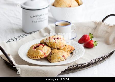 Torte di mano (mini torte) con un riempimento di fragola e decorazioni di cuore Foto Stock