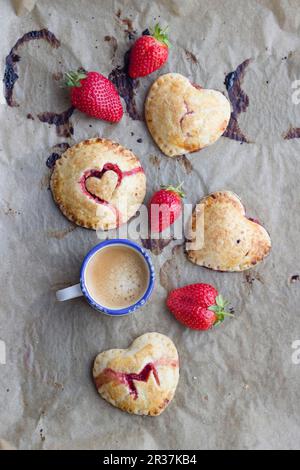 Torte di mano (mini torte) con un riempimento di fragola e decorazioni di cuore Foto Stock