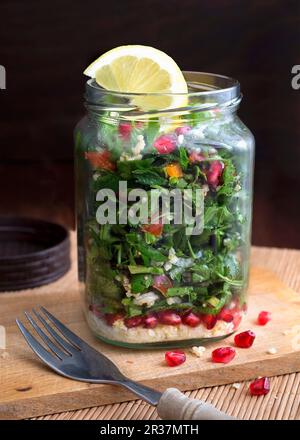 Millet taboule in un vasetto di vetro con i semi di melograno, prezzemolo e menta Foto Stock