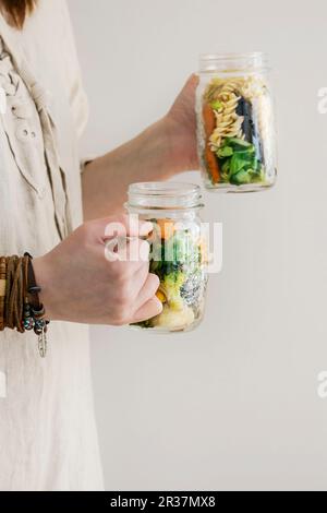 Una donna in un abito di lino che tiene due vasetti per insalata Foto Stock