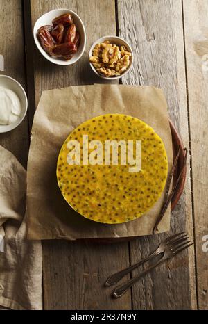 Mascarpone e yogurt greco cheesecake con una data e una base in legno di noce, guarnita con maracuja Foto Stock