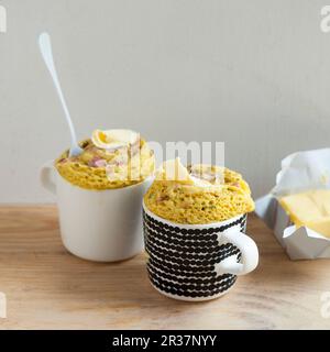 Tortine di tazza saporite con prosciutto a dadini e una liretta di burro sulla parte superiore Foto Stock