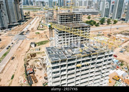 vista aerea delle gru di lavoro in cantiere. nuova area residenziale urbana con alti edifici di appartamenti in costruzione. Foto Stock