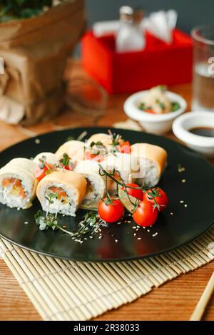 Sushi Rolls con salmone, formaggio fresco e pomodori cocktail Foto Stock