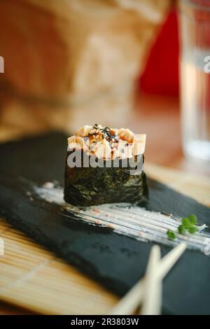 Sushi singolo con omelette tritate su un piatto nero Foto Stock