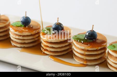 Diverse pile di mini pancake con sciroppo d'acero, mirtilli e menta Foto Stock