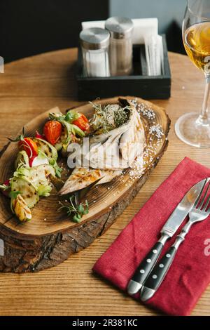 Sgombri alla griglia e verdure su un asse di legno Foto Stock