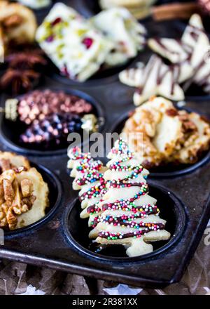 Vari biscotti di Natale decorati in un vassoio per muffin Foto Stock