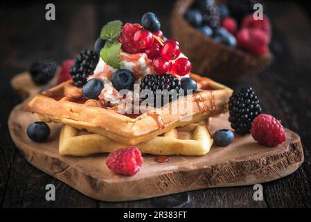 Cialde belghe con gelato e frutti di bosco su una tavola di legno Foto Stock