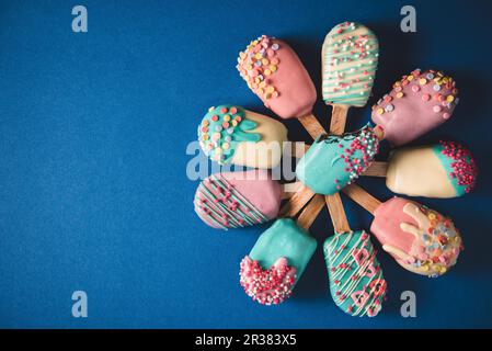 Diversi schiocchi di torte a forma di lollie di ghiaccio con glassa dai colori vivaci Foto Stock