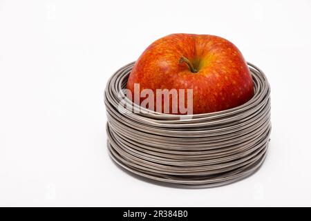 Cavo Apple: tutta la mela rossa in bobine di filo di alluminio isolato su sfondo bianco Foto Stock