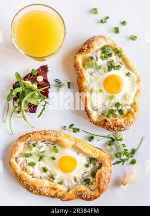 Mini pizze con uova fritte e un bicchiere di succo d'arancia Foto Stock