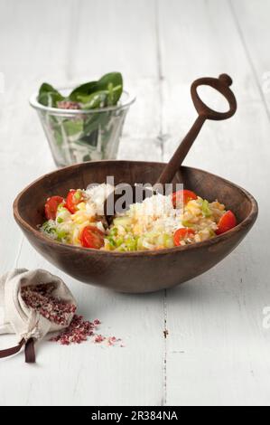 Risotto di lenticchie rosse con pomodori ciliegini, parmigiano e insalata di spinaci Foto Stock