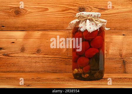 Barattolo di pomodori marinati al marrone vintage superficie di legno Foto Stock