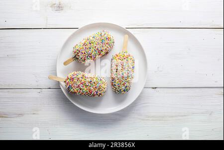 Tre lollie di ghiaccio con bastoni, coperte in centinaia e migliaia Foto Stock