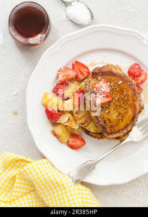 Toast alla francese vegano con ananas griddled, fragole, fiocchi di cocco e sciroppo d'acero Foto Stock