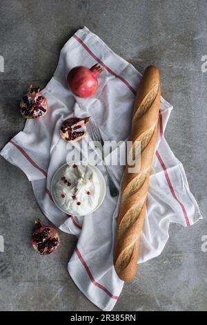 Burrata (formaggio italiano fresco a base di mozzarella e panna) servita con baguette e melograno Foto Stock