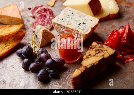 Un piatto di antipasti con diversi tipi di formaggio, salame, uva e pane Foto Stock