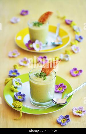 Zuppa di avocado in due bicchieri con pane tostato e crescione fresca, e fiori decorativi primavera crochet Foto Stock