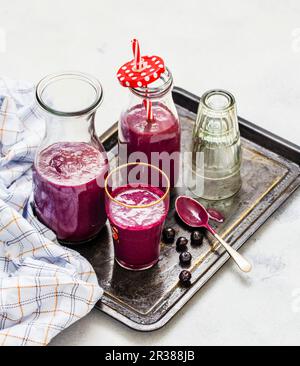 Frullati di mirtillo con porridge in bottiglia e un bicchiere su un vassoio Foto Stock