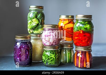 Vasetti di verdure appena sott'aceto impilati di fronte a uno sfondo grigio Foto Stock