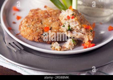 Tortine di granchio parzialmente mangiate con pepe rosso Foto Stock