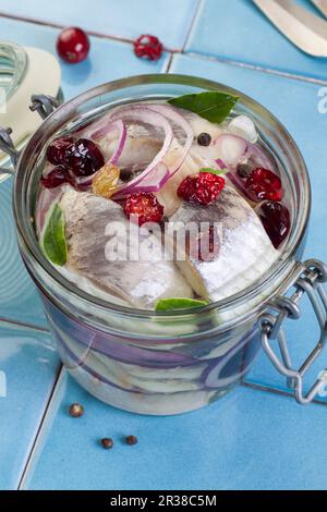 Filetti di aringhe marinati con mirtilli rossi e uva passa in un vasetto Foto Stock