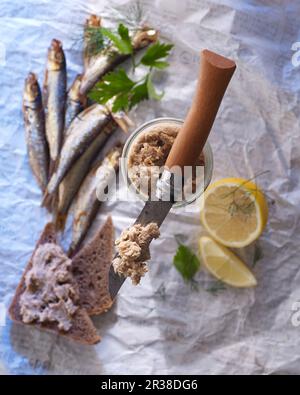 Sgombro su un coltello Opinel, con pane integrale, sgombro fresco e spicchi di limone Foto Stock