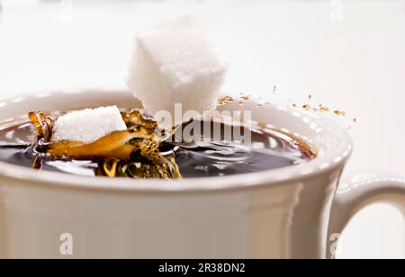 Grumi di zucchero che cadono in una tazza di caffè Foto Stock