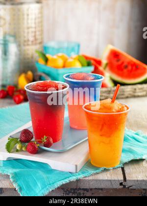 Tre diversi slussi fruttati in tazze di plastica Foto Stock