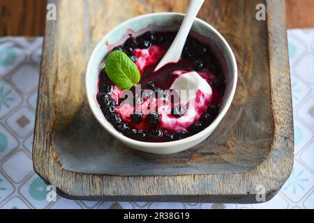 Yogurt con zucchero e mirtilli surgelati su un vassoio di legno (vegan) Foto Stock