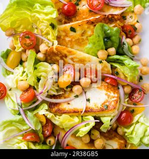 Halloumi fritto in padella con pomodori ciliegini, ceci e lattuga Foto Stock