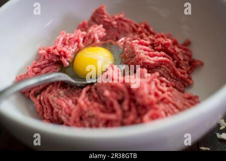 Ingredienti per polpette: Carne tritata e tuorlo d'uovo in un recipiente Foto Stock