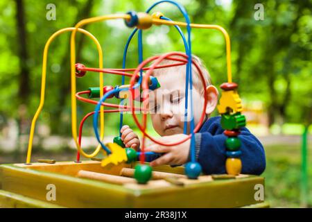 Capretto piccolo ragazzo gioca con un multicolore giocattolo logico Foto Stock