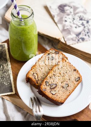 Due fette di pane di banana senza farine (mandorla e farina di cocco) con noci, servito con frullato verde Foto Stock