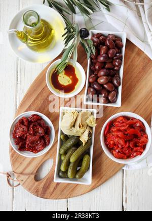 Piatto antipasto - pomodori secchi e capsicum, olive kalamata, cetriolini, carciofi, panini, olio d'oliva (con aceto balsamico) e crusca d'oliva Foto Stock