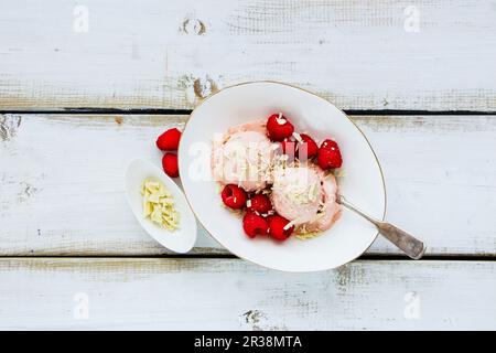 Ciotola di gelato al lampone organico con frutti di bosco freschi e cioccolato bianco su fondo ligneo Foto Stock