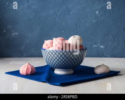 Meringhe rosa e bianche in una ciotola blu Foto Stock