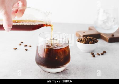 Caffè ghiacciato, caffè Cold Brew con ghiaccio su sfondo grigio chiaro brillante, bevanda rinfrescante Foto Stock